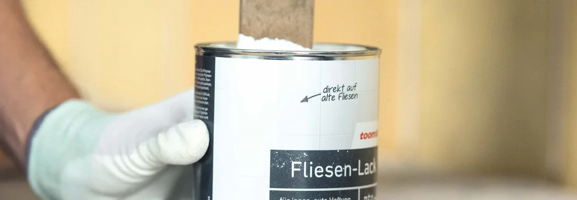 Person hält einen Farbeimer in der Hand.